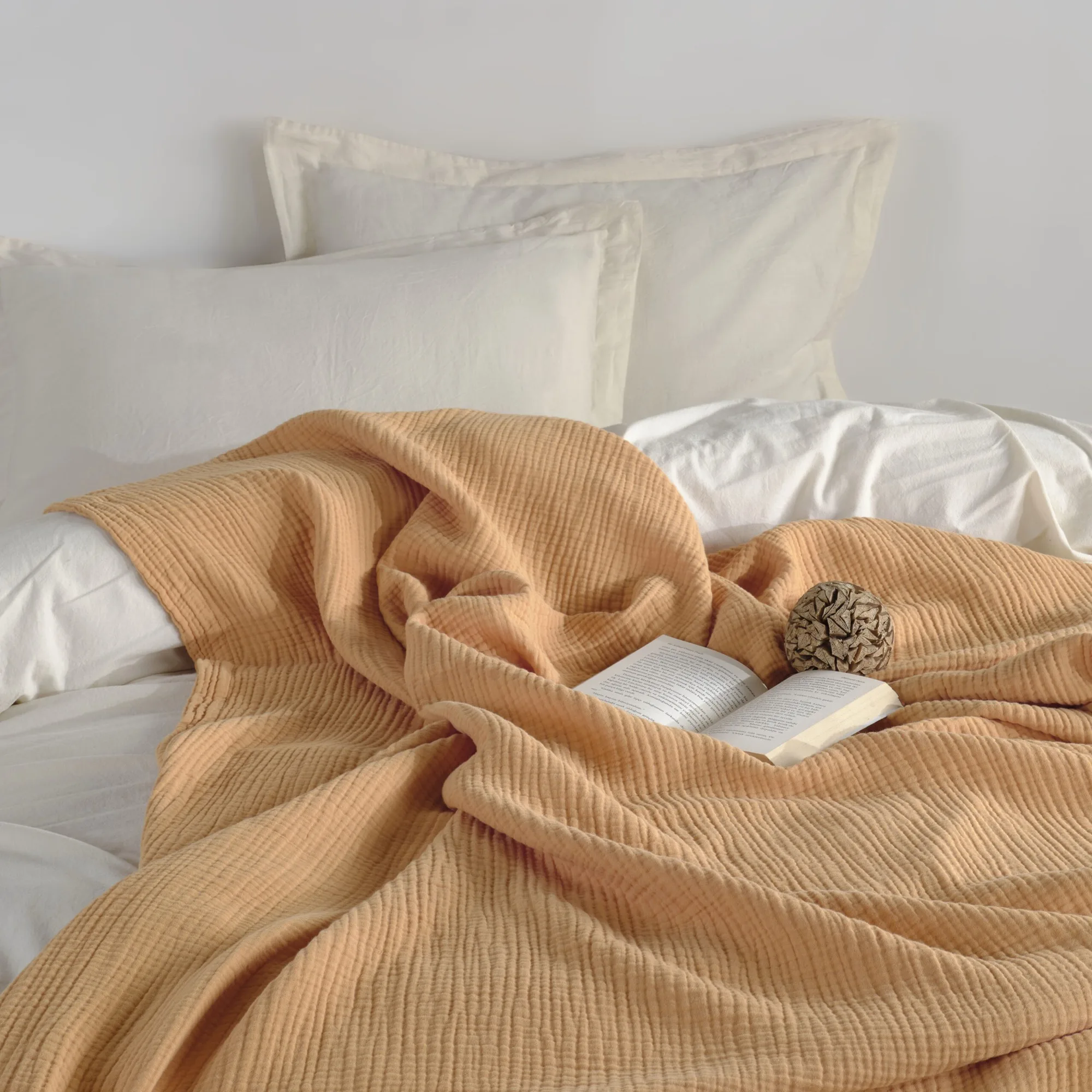 Muslin throw blanket on a bed with white bed linen